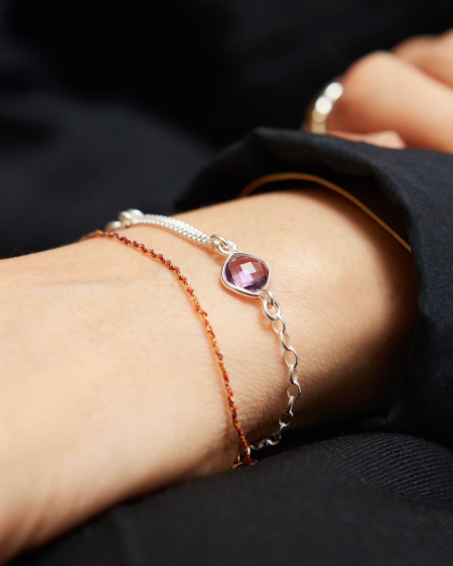 Close-up of a wrist wearing two bracelets with a dark background