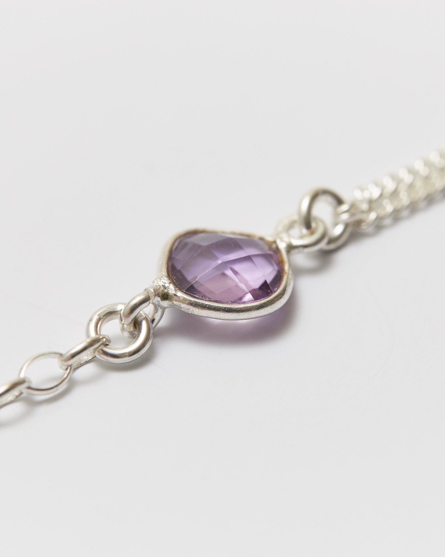 Silver bracelet with an amethyst on a light gray background