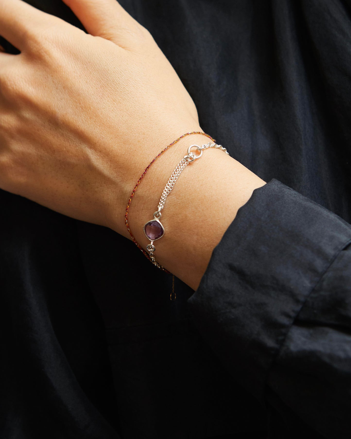 Close-up of a wrist wearing two bracelets with a dark background