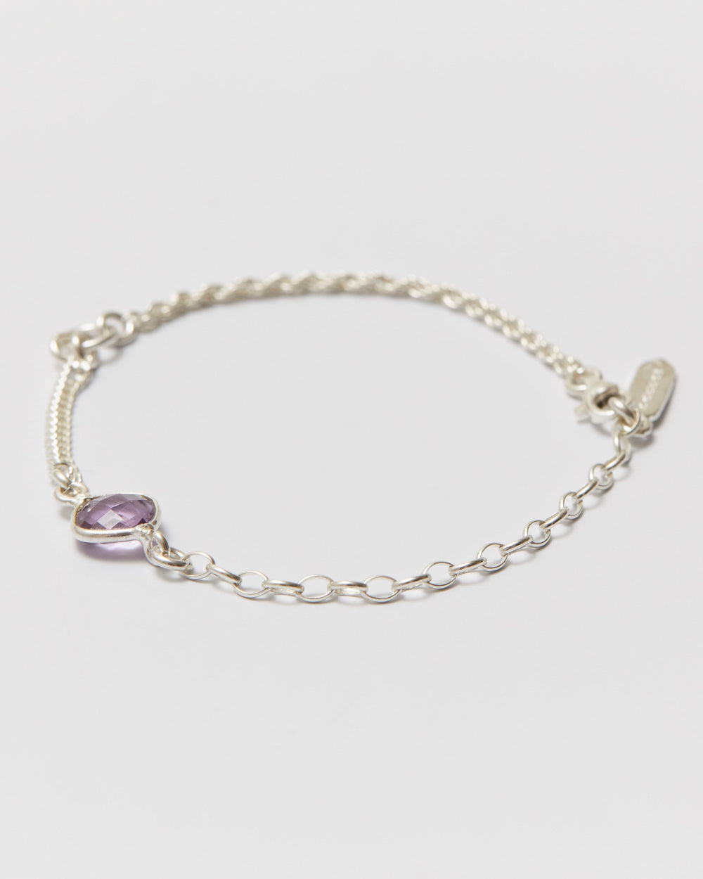 Silver bracelet with a purple gemstone on a light gray background