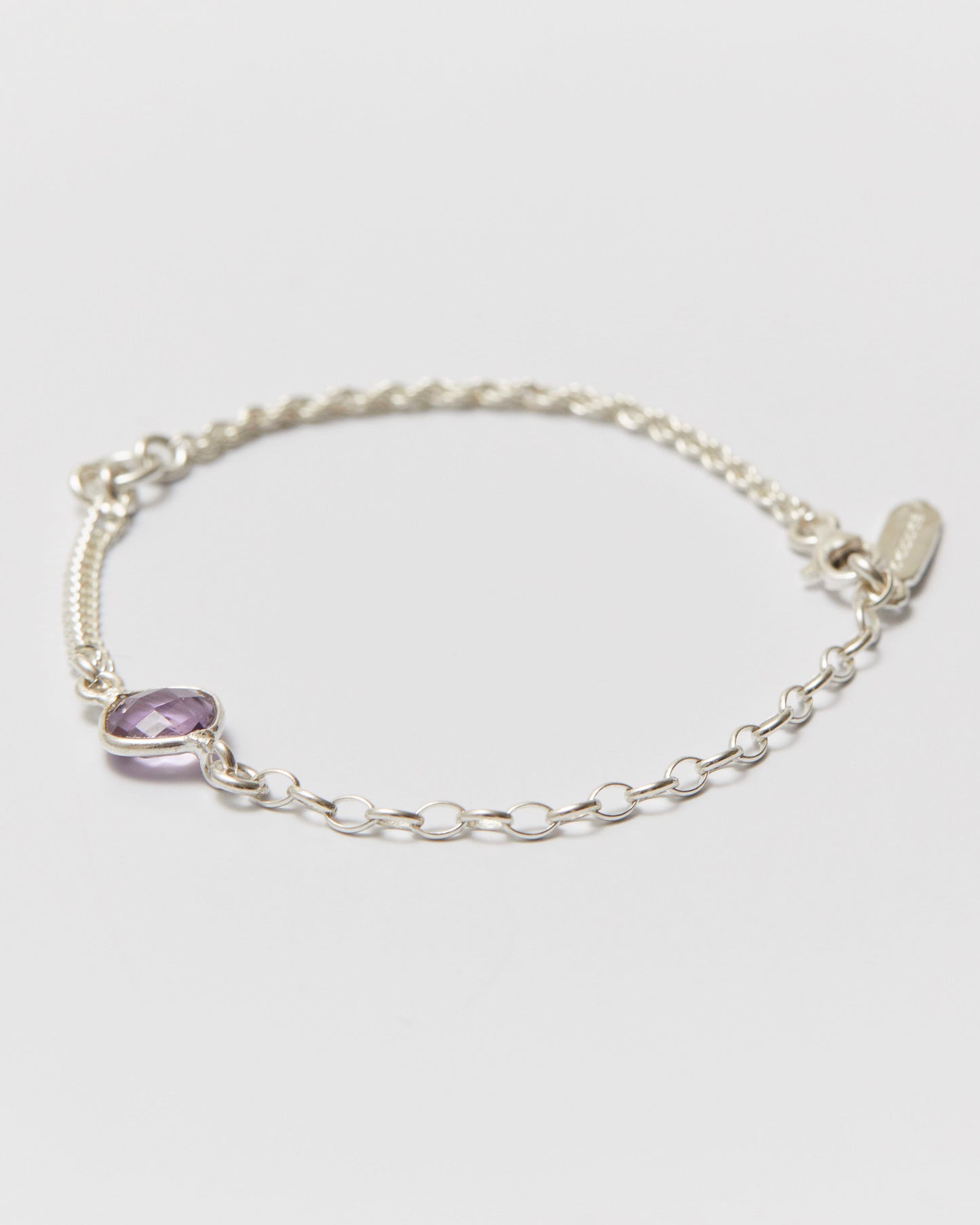 Silver bracelet with a purple gemstone on a light gray background