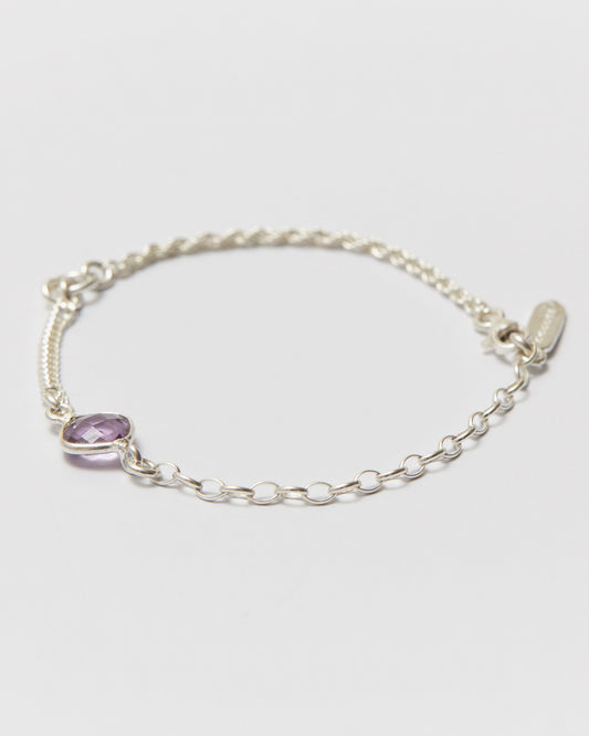 Silver bracelet with a purple gemstone on a light gray background