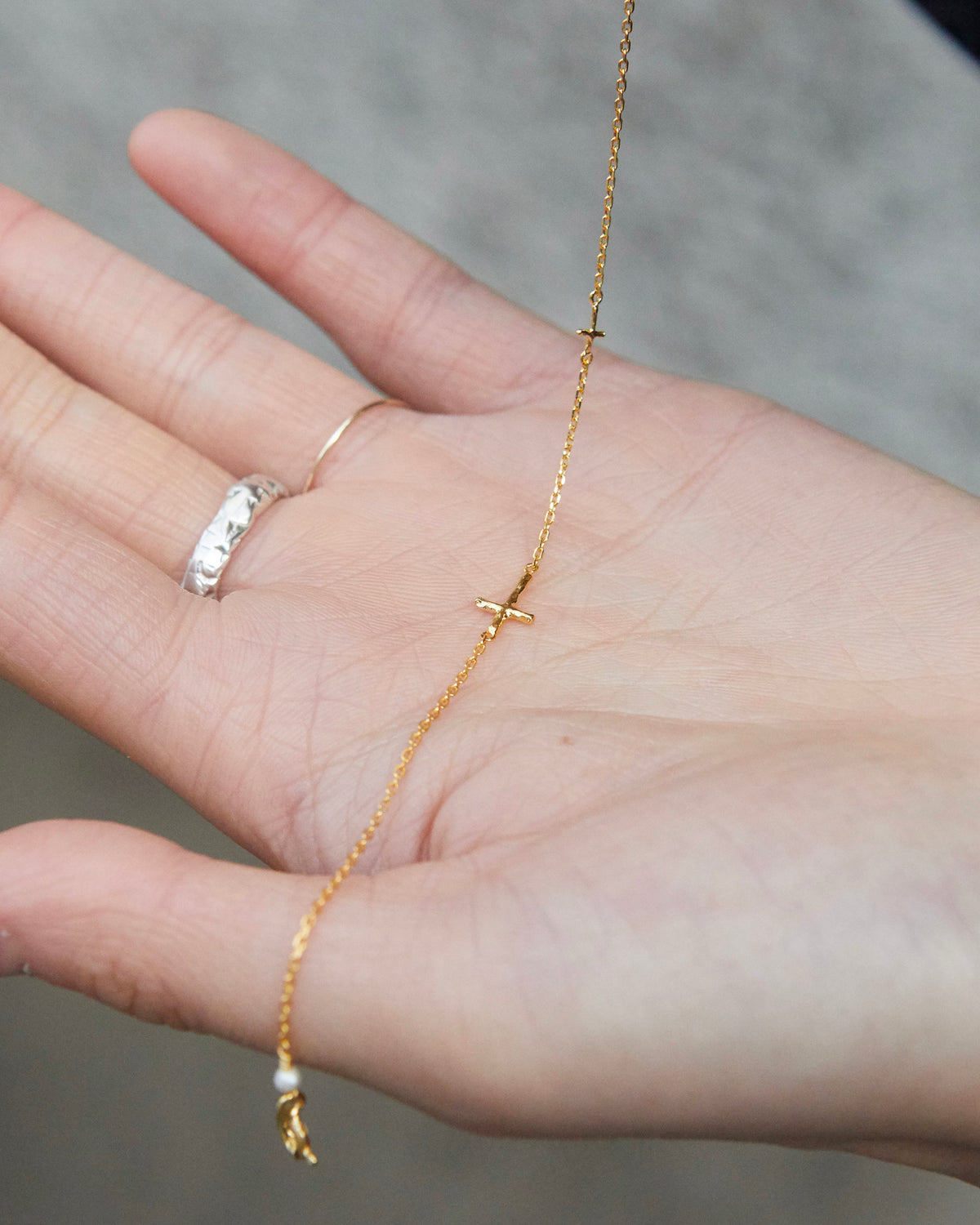 cross axis chain bracelet in gold – draped across an open palm to show the fine chain | HANNA543