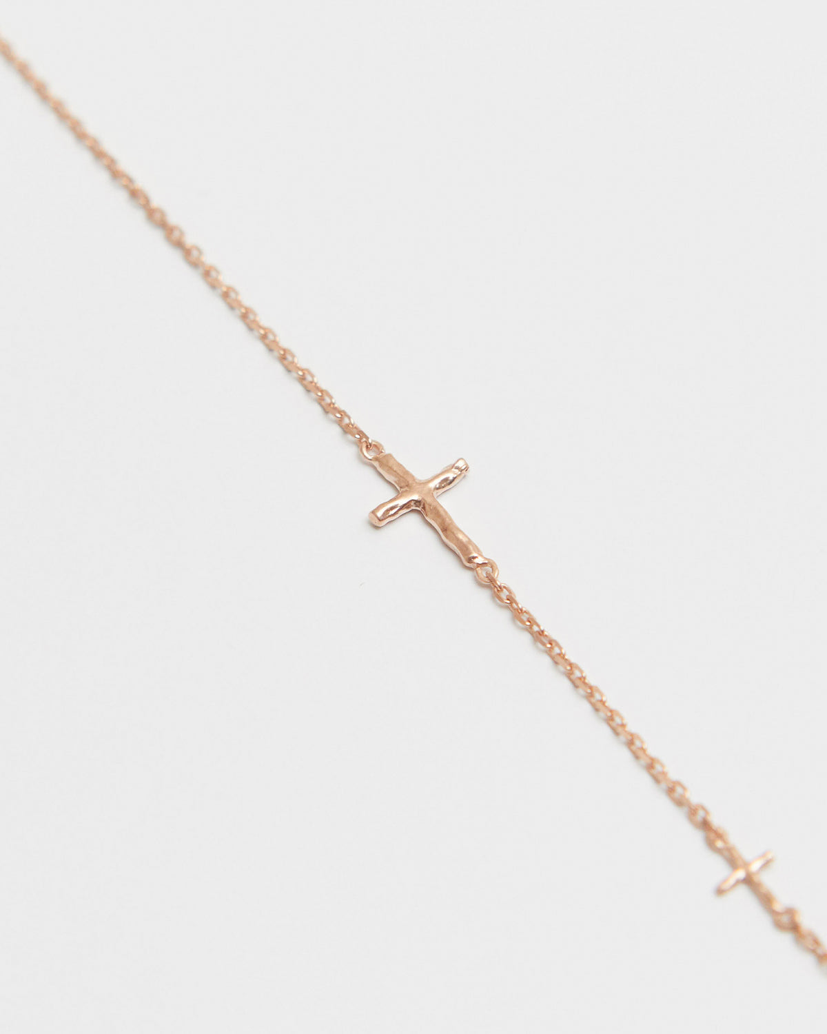 cross axis chain bracelet in pink gold – close-up of the small cross charm on a fine chain | HANNA543