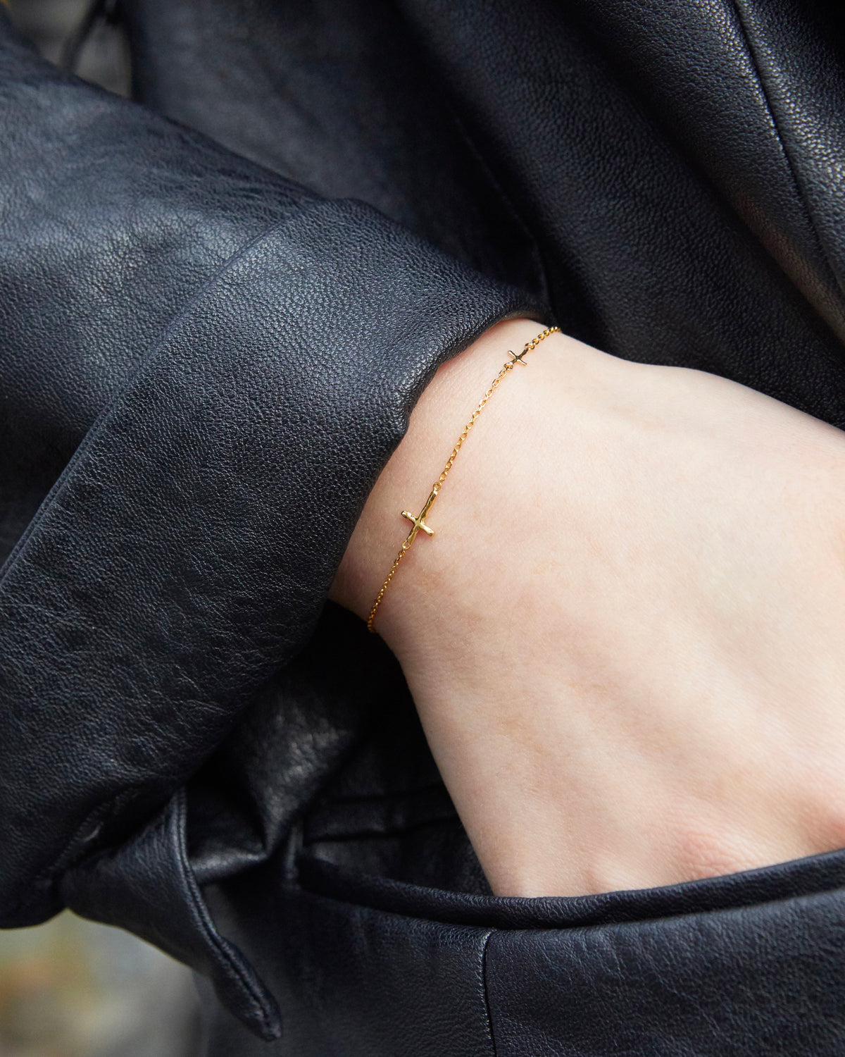 cross axis chain bracelet in gold – worn on the wrist with a black leather jacket | HANNA543