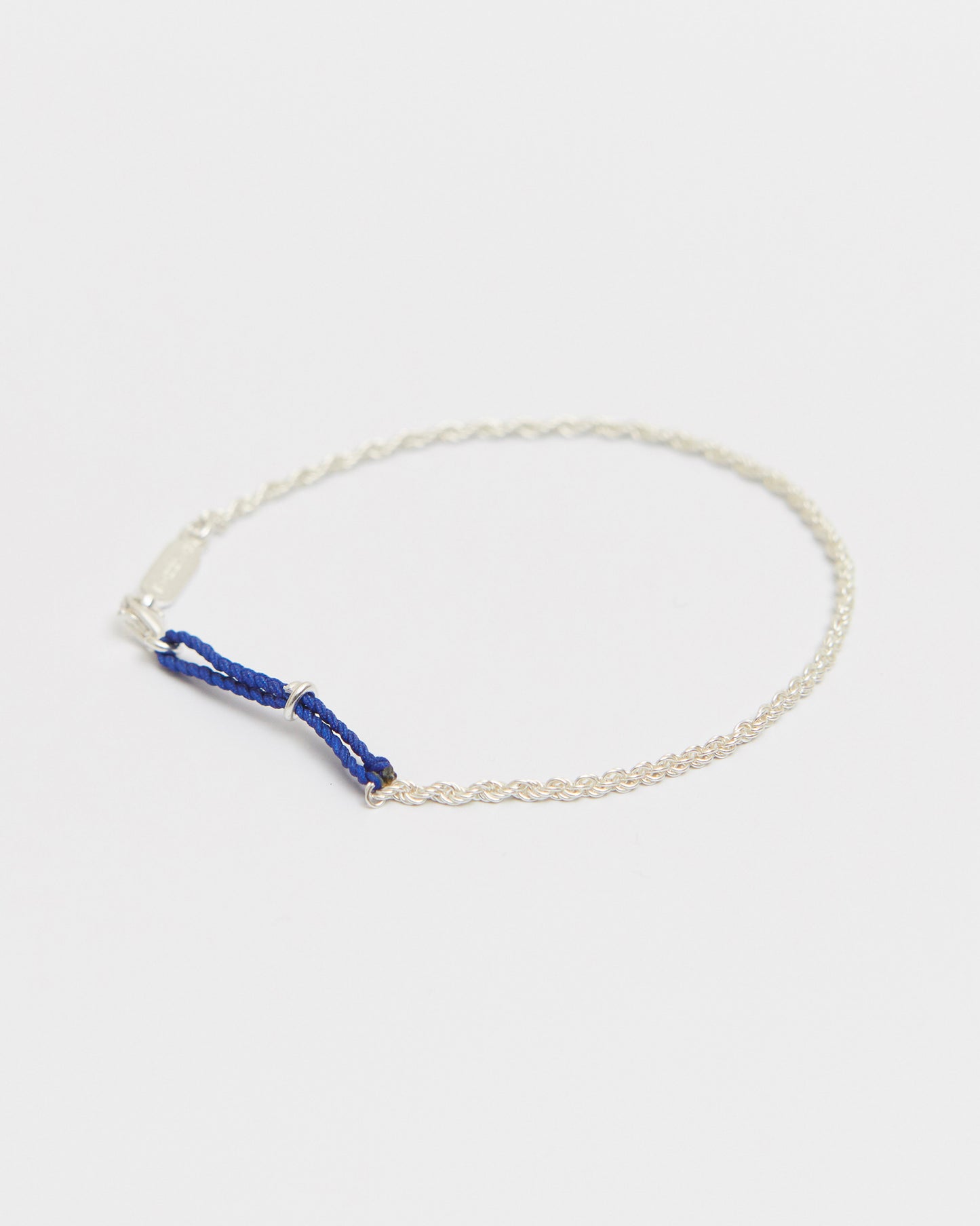 Sterling silver bracelet featuring braided cobalt blue cord accent and delicate chain for modern minimalist styling.