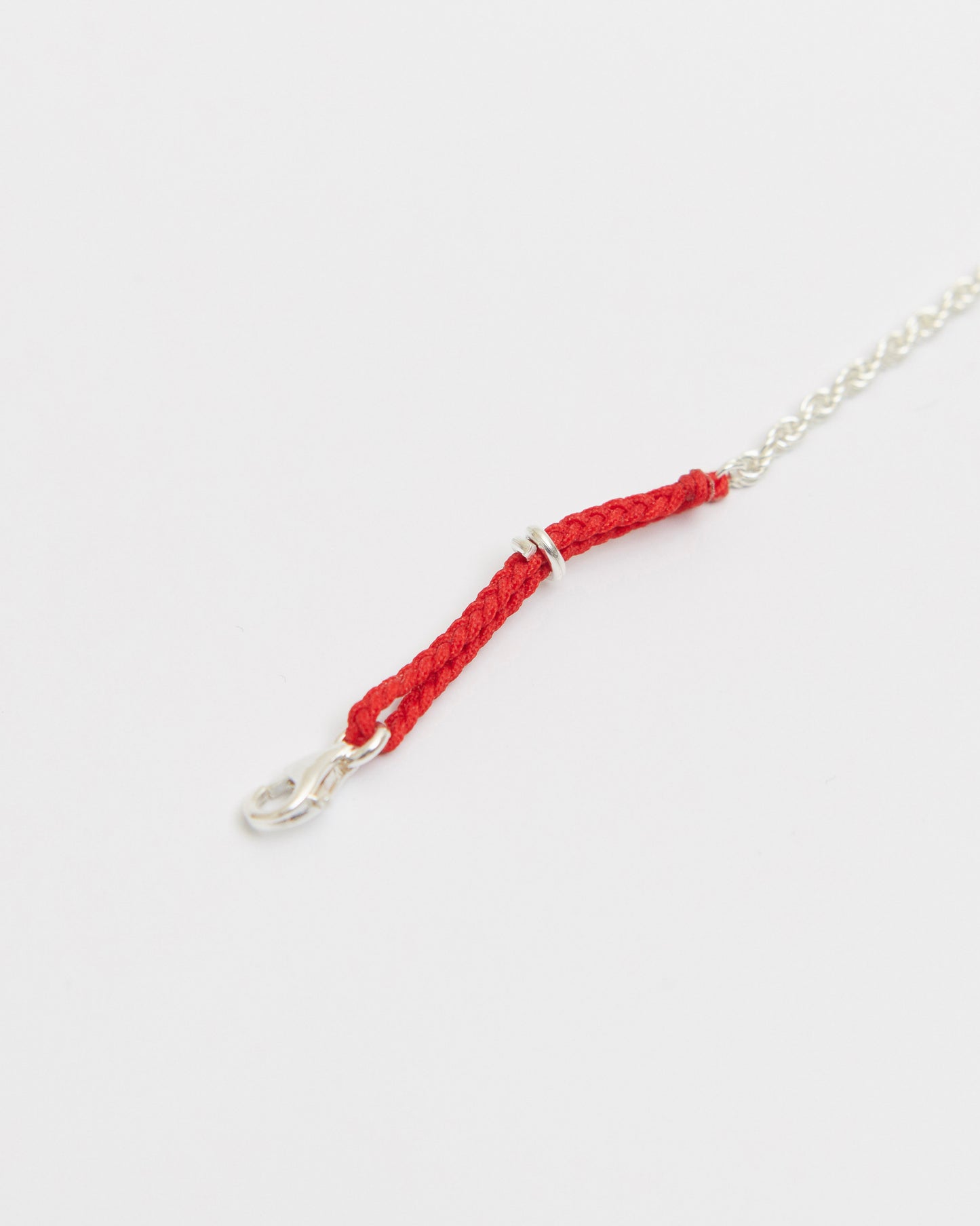 Close-up of braided red cord sterling silver bracelet showcasing woven texture and silver clasp.