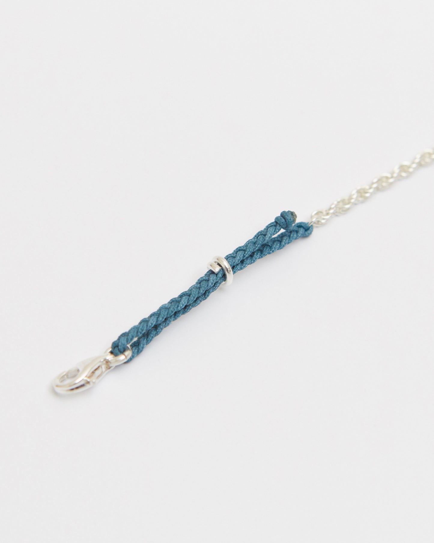Macro close-up of braided vintage green cord bracelet with sterling silver hardware and delicate chain detail.