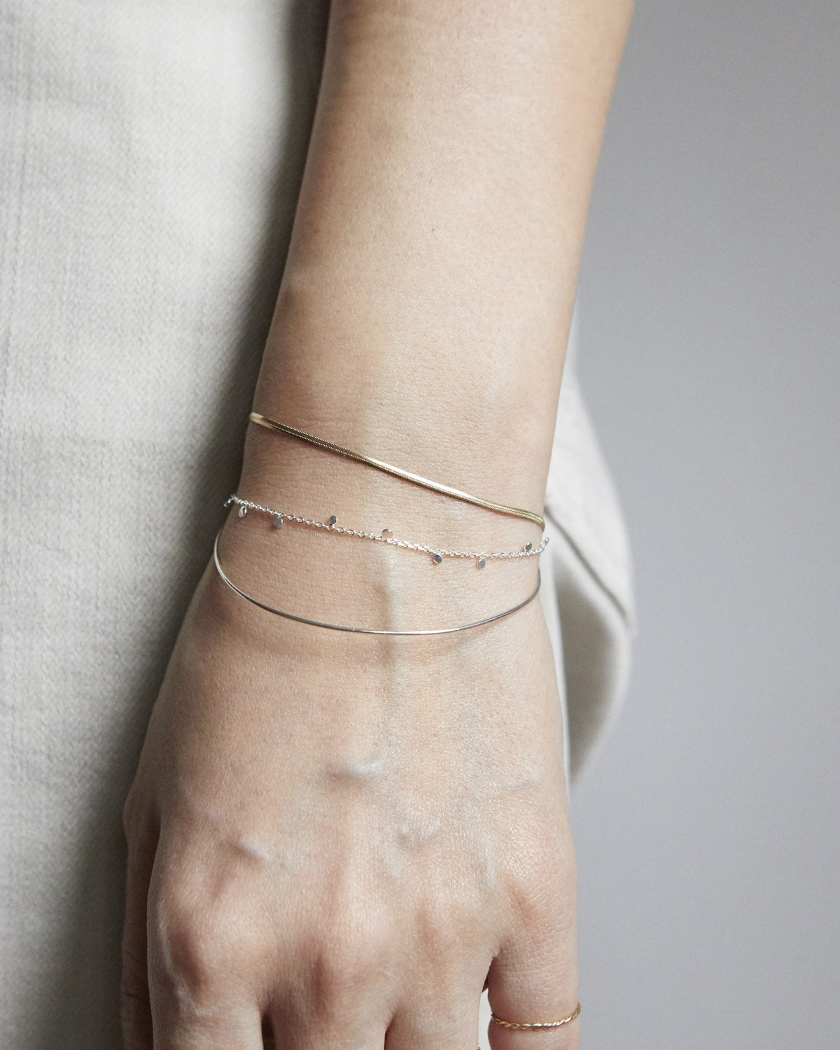 Wrist wearing a silver dot chain bracelet layered with thin bangles – HANNA543 B96 dew drop garland