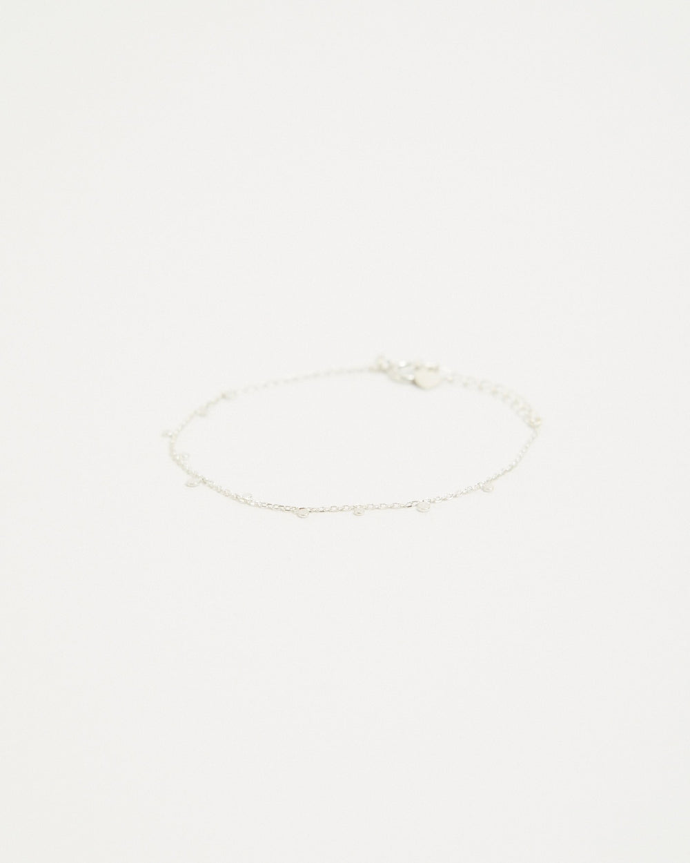 Sterling silver dot station chain bracelet laid flat on a light background – HANNA543 B96 dew drop garland