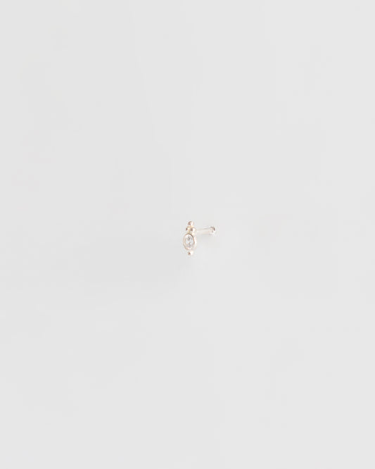 delicate silver stud earring worn on ear, minimal editorial jewelry styling