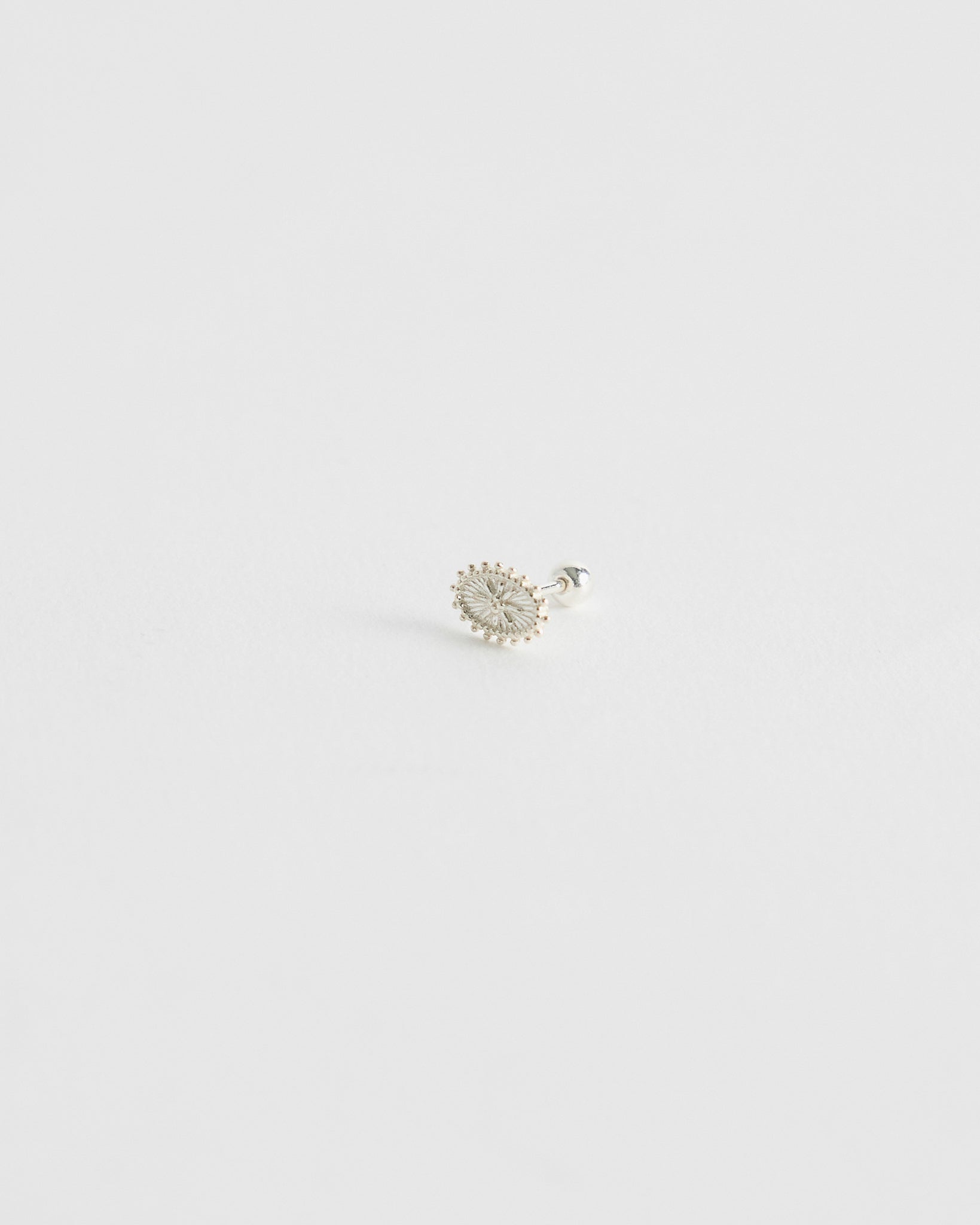 Silver earring on a light gray background