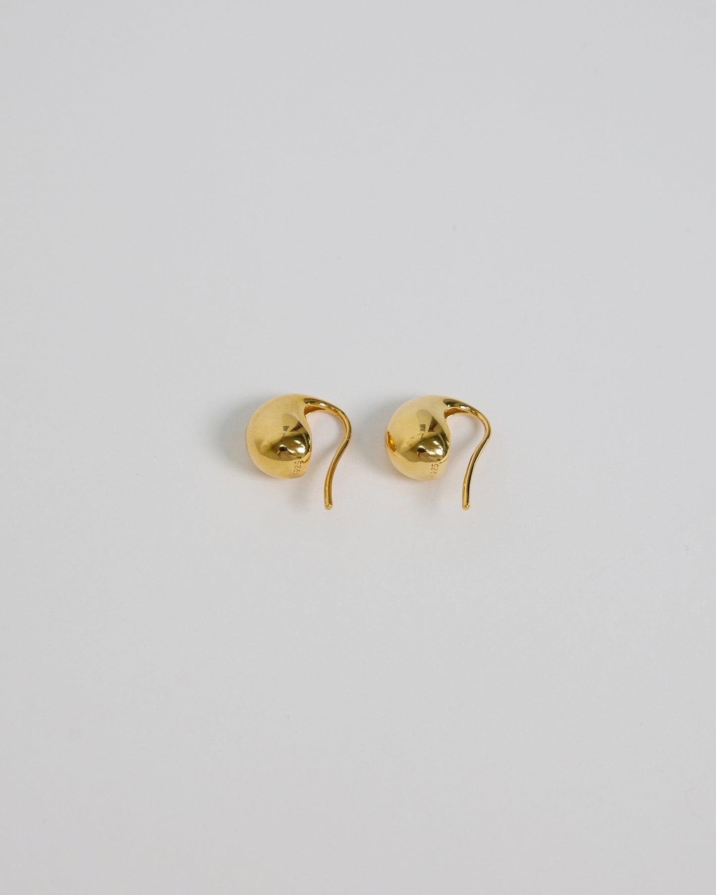 Silver fluid drop earring held in hand, showcasing size and organic shape
