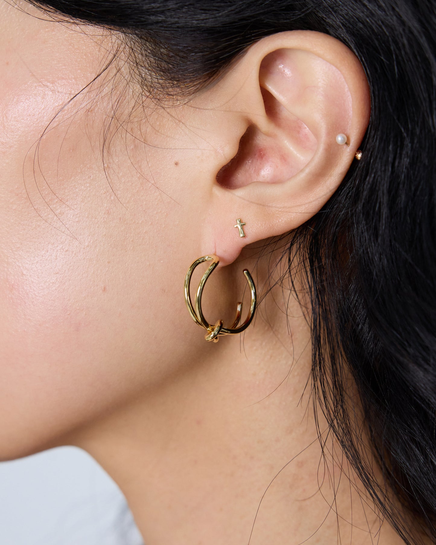 gold knot hoop earrings worn on ear minimal everyday hoop earrings stylish ear styling gold jewelry daily outfit