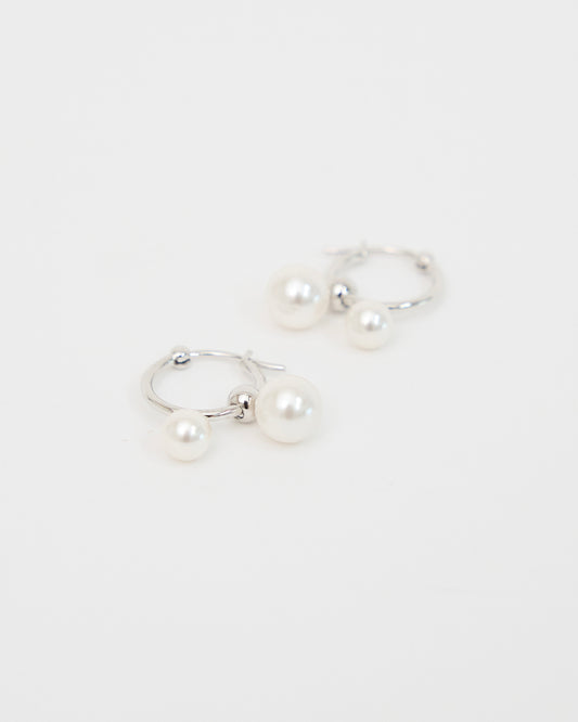 Front-facing product image of silver-tone hoop earrings with two white pearl drops, arranged neatly on a white background to show the full pair and balanced design.
