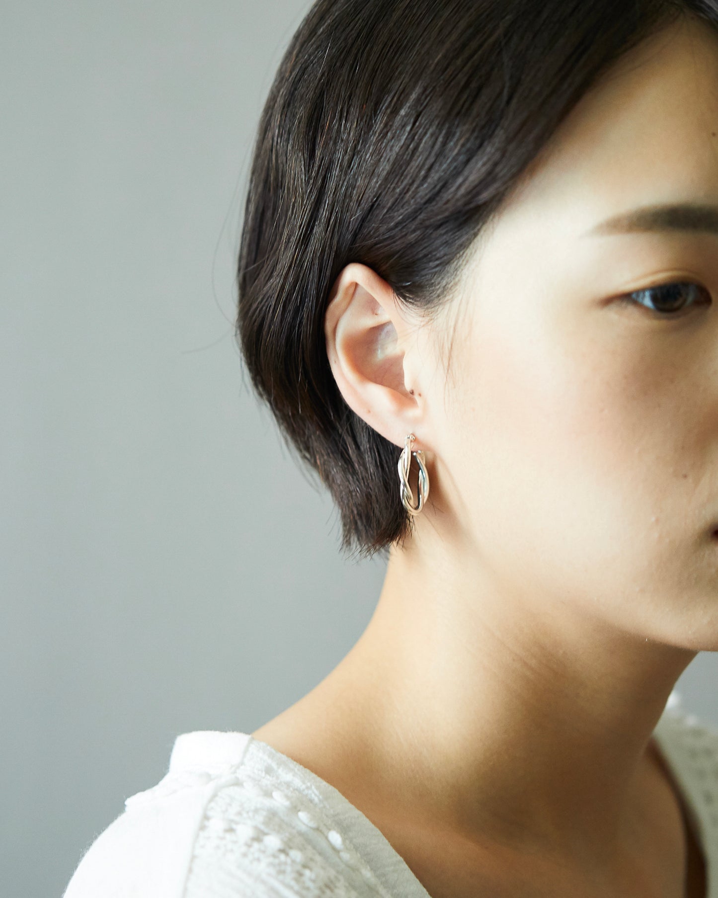 Styling of HANNA543 E324 twisted silver hoop earrings on ear. Daily minimalist jewelry look inspired by BTS Jimin