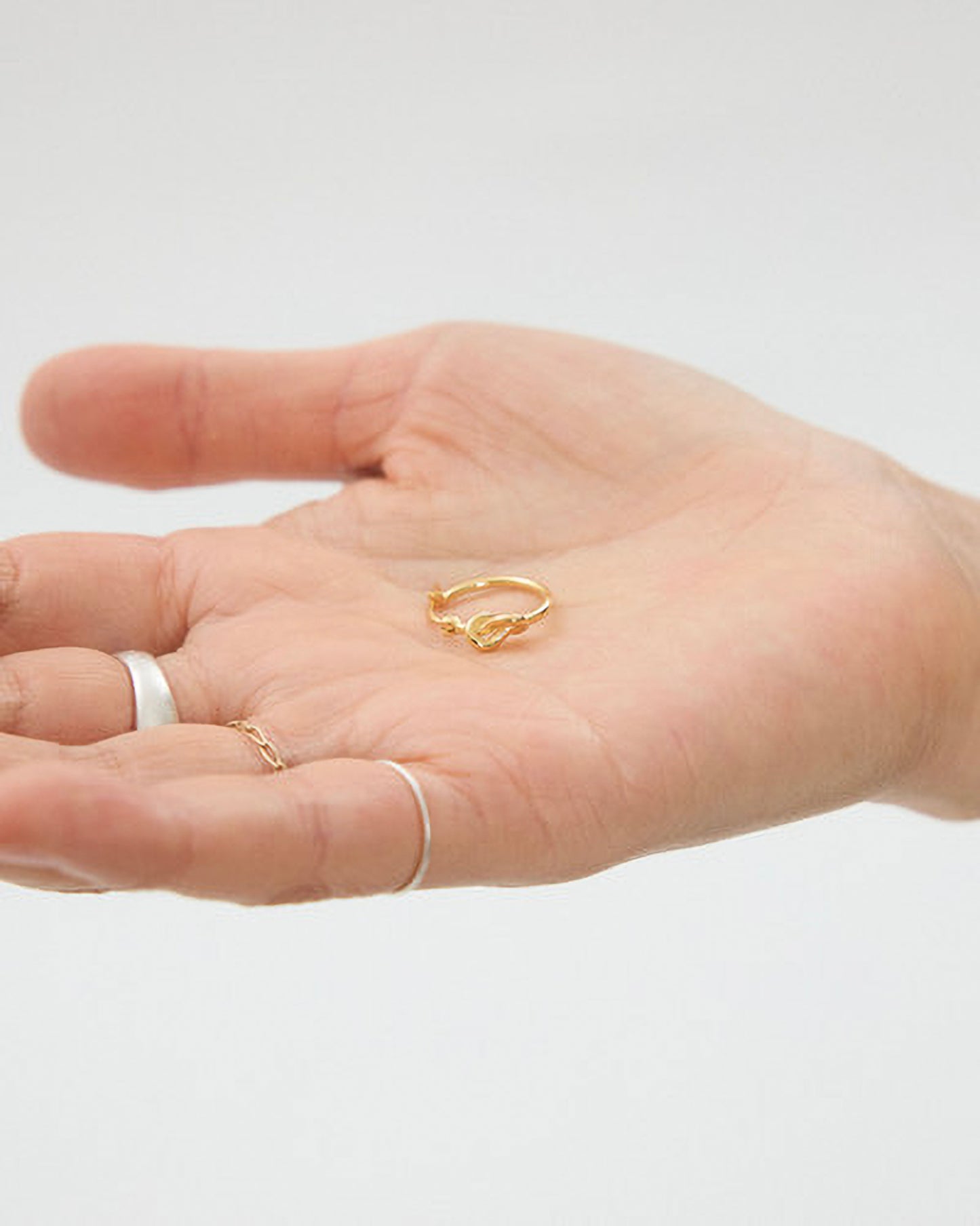 Hand wearing gold rings on a plain background