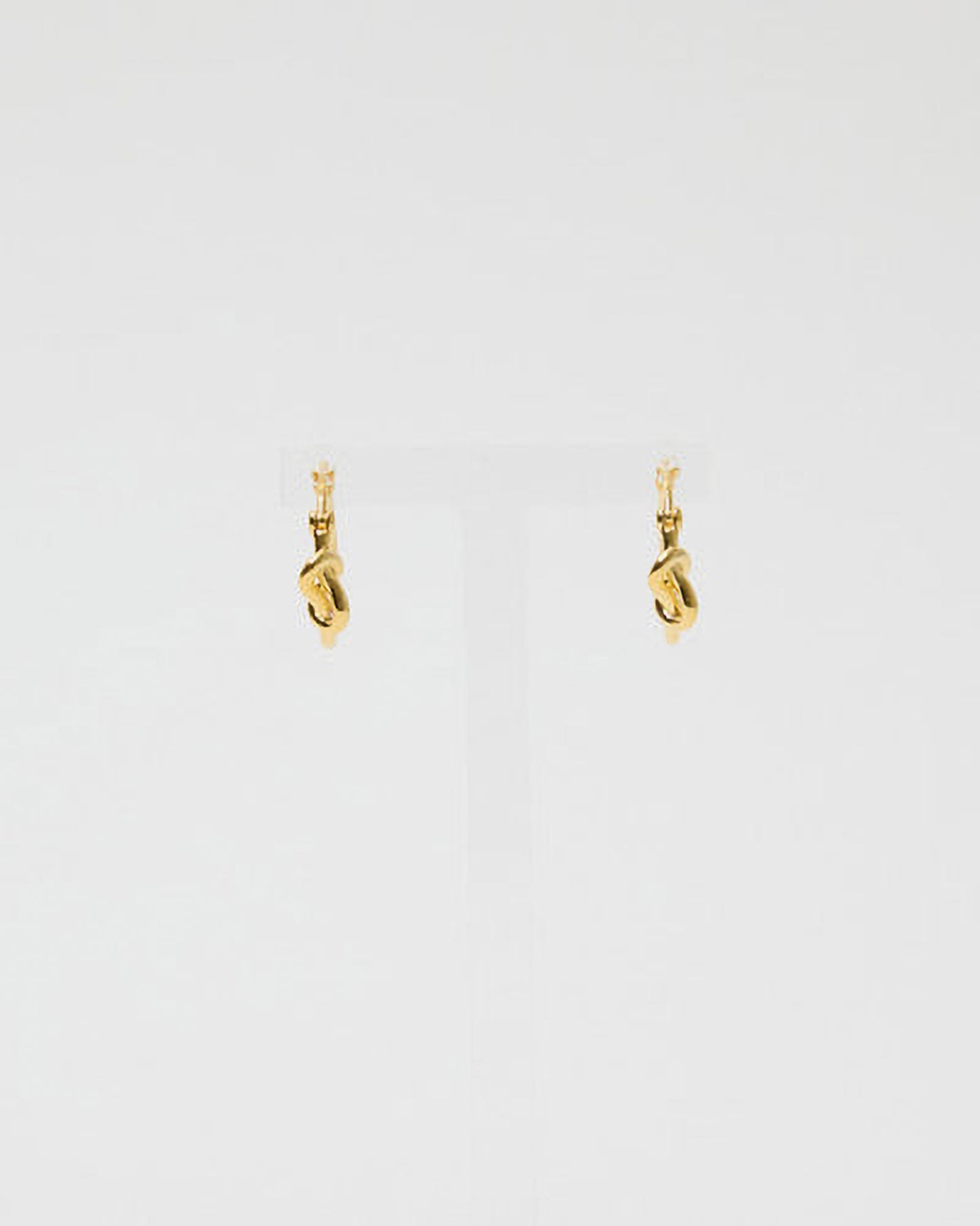 Gold earrings on a light gray background