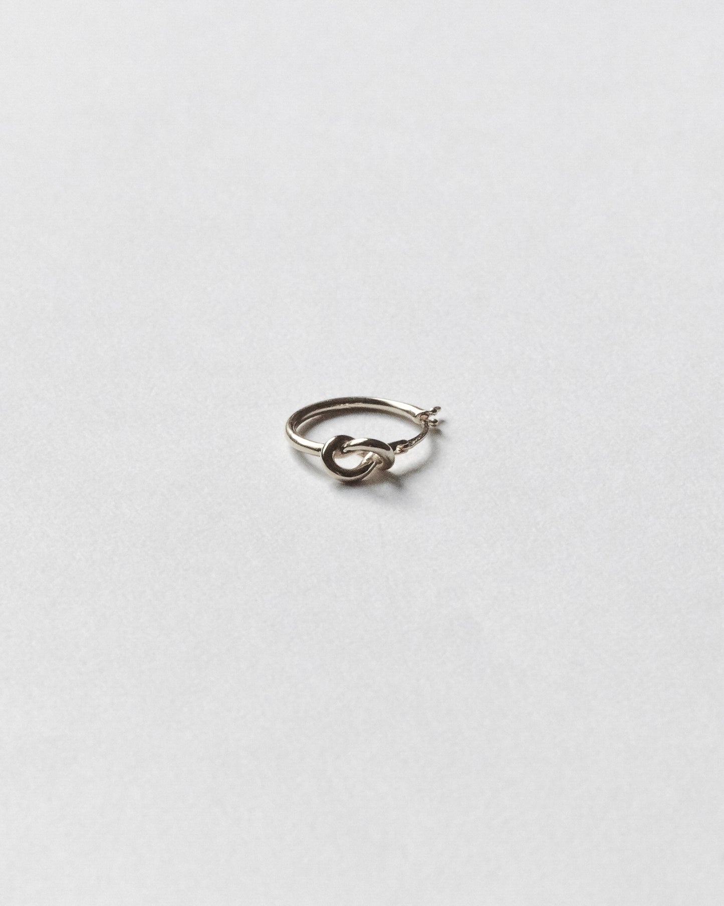 Silver hoop earring on a light gray background