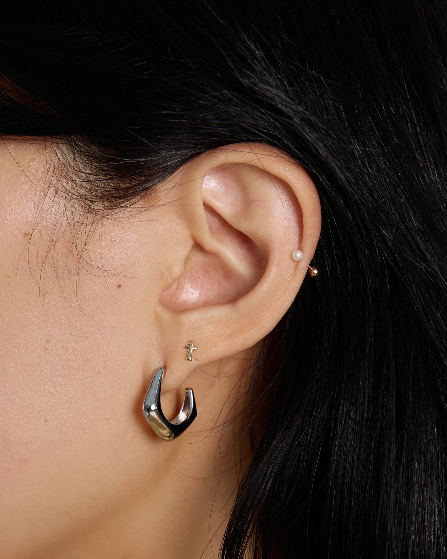 silver chunky curved hoop earrings worn on ear, modern sculptural silver jewelry look