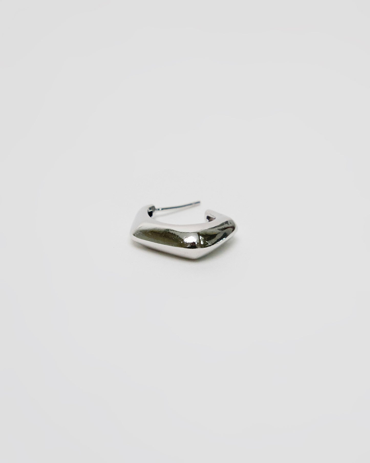 single silver sculptural hoop earring isolated on clean background, minimalist product photography
