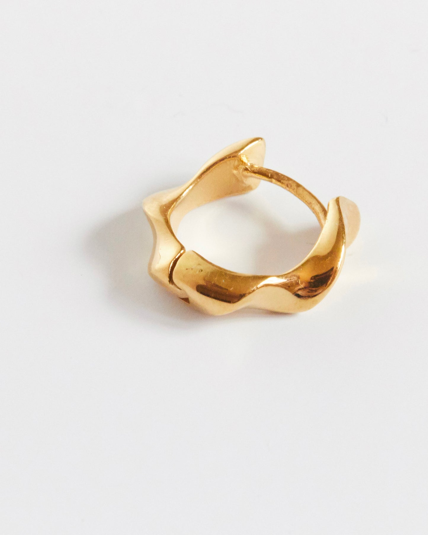 Gold earring on a light gray background