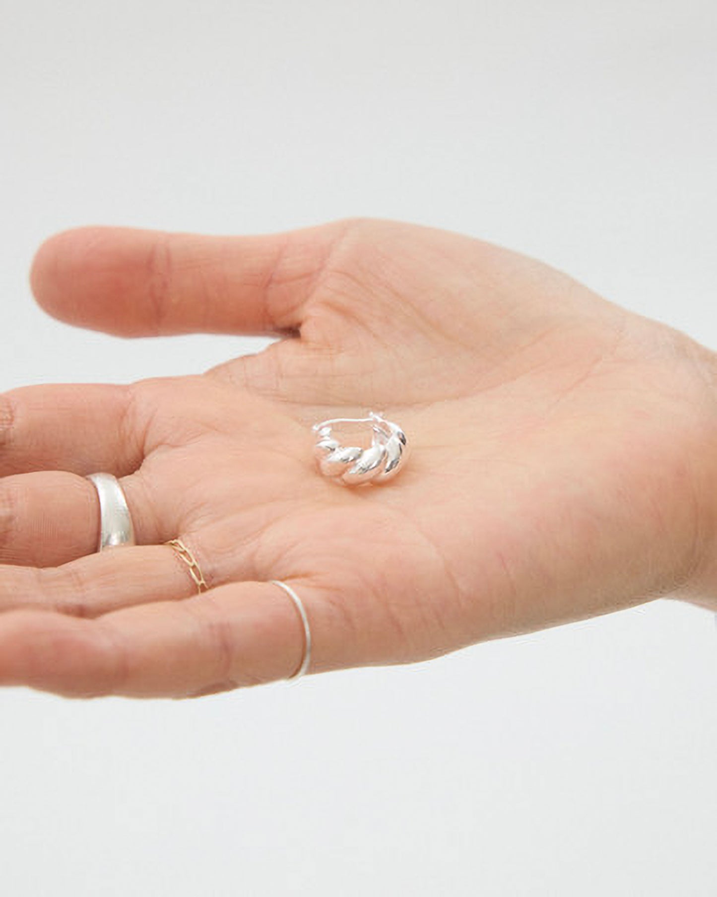 Hand the silver earring on a plain background