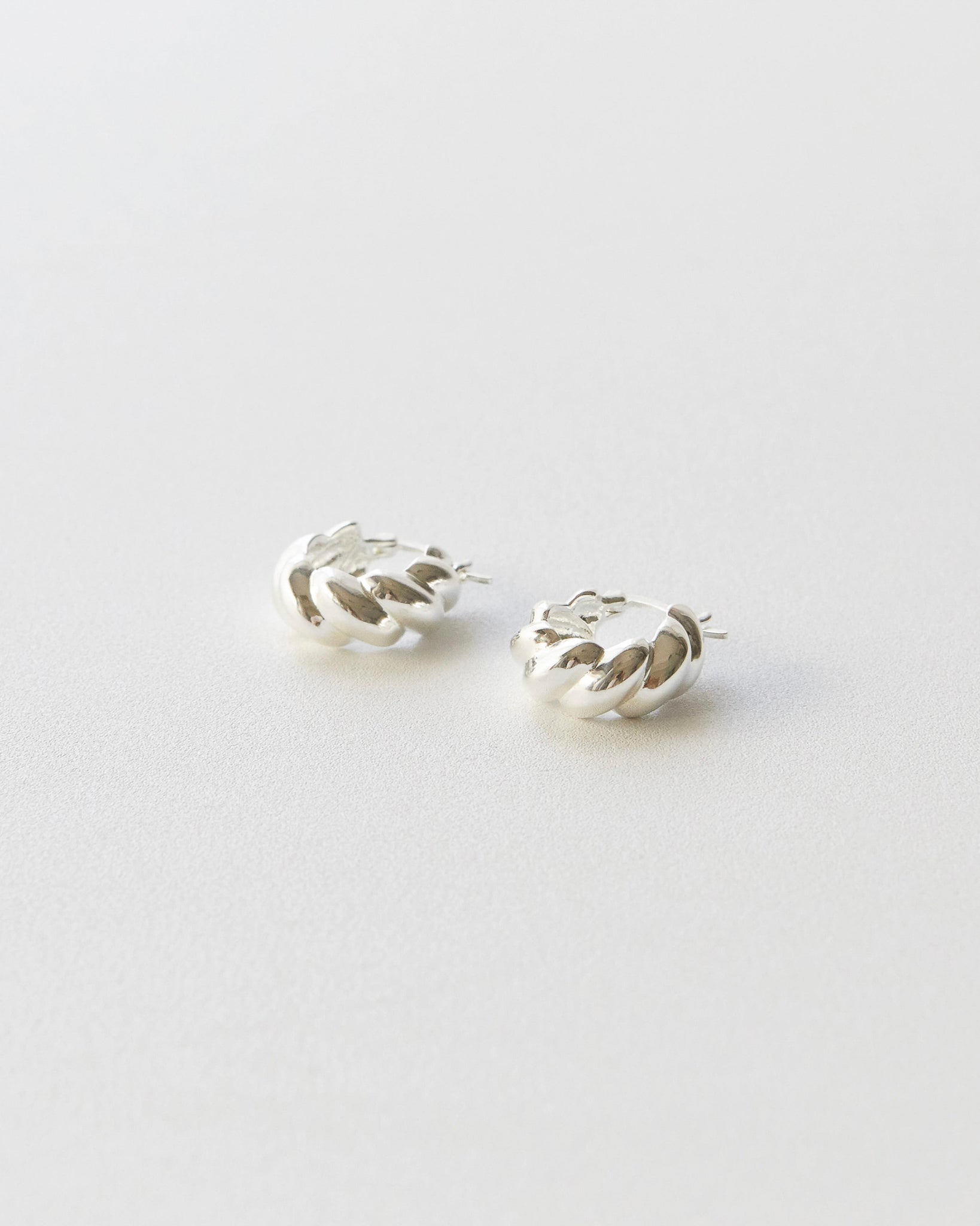 Silver hoop earring on a light gray background