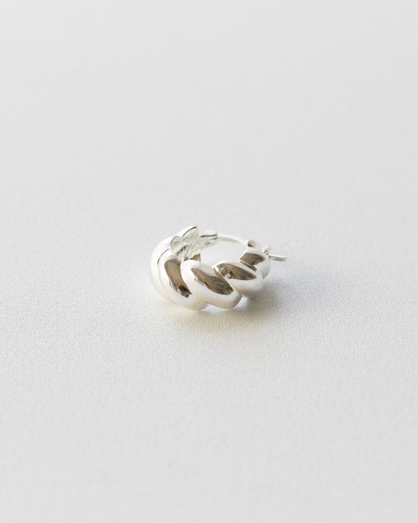 Silver hoop earring on a light gray background