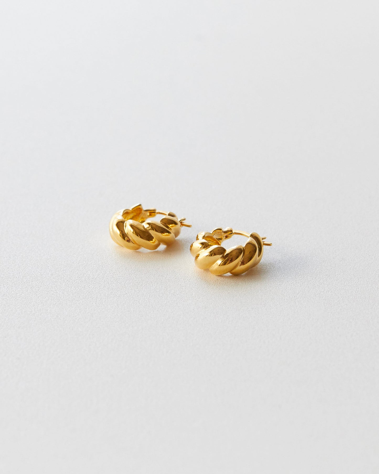 Pair of gold hoop earrings on a light gray background