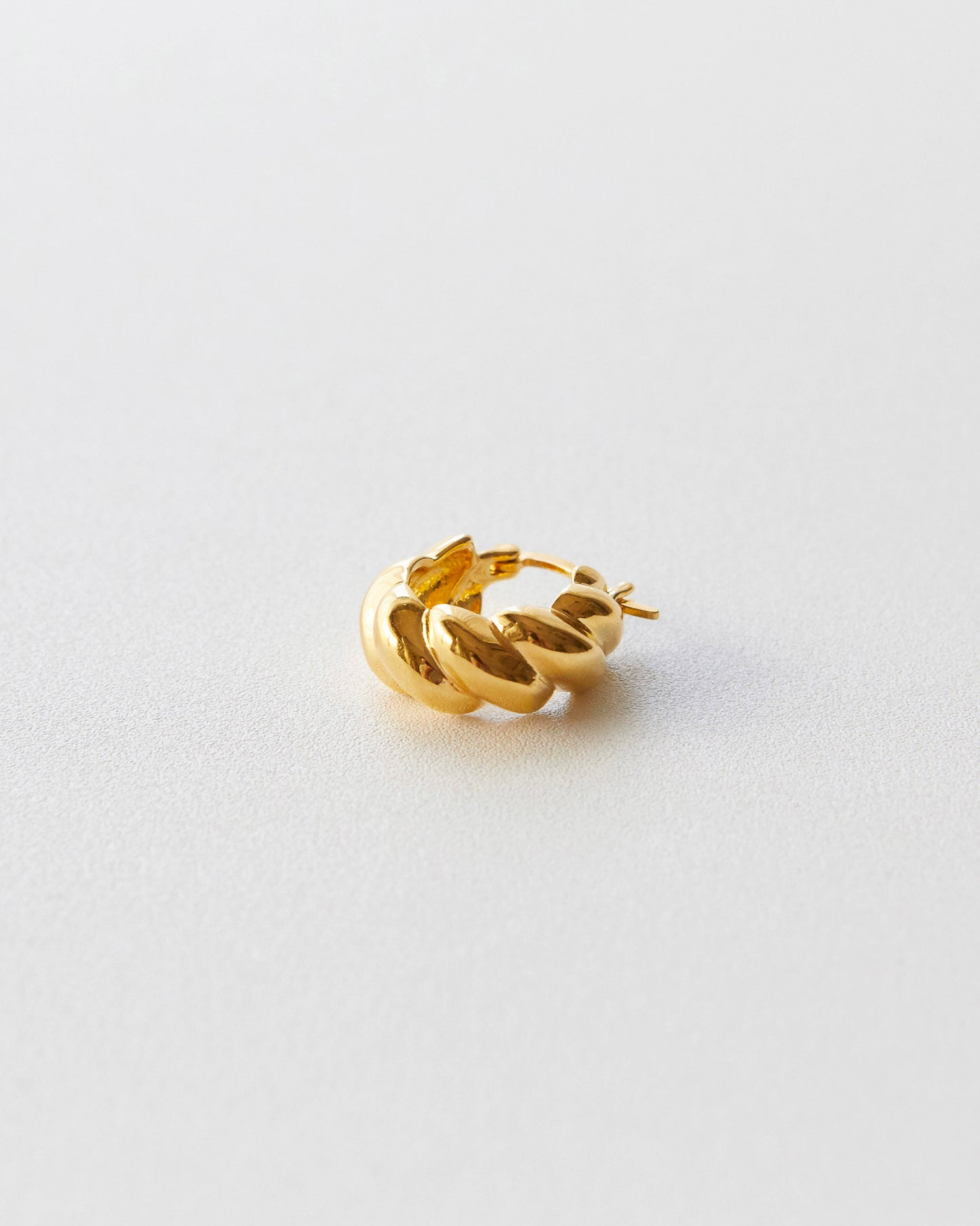 Gold hoop earring on a light gray background
