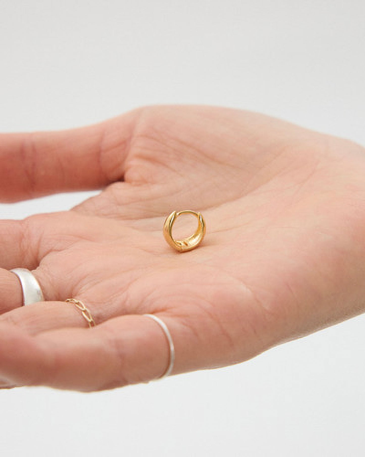 Gold ring on a hand with a plain background