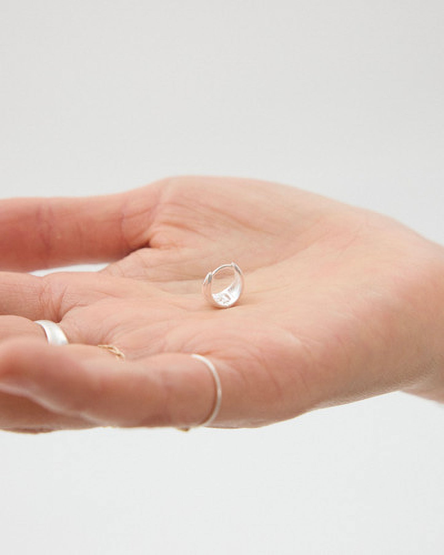 Hand wearing a silver ring on a plain background