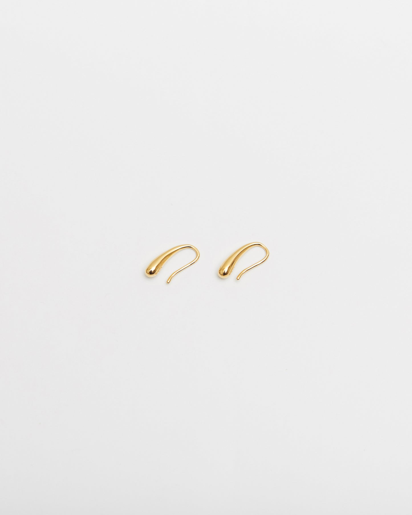 Gold hoop earrings on a light beige background