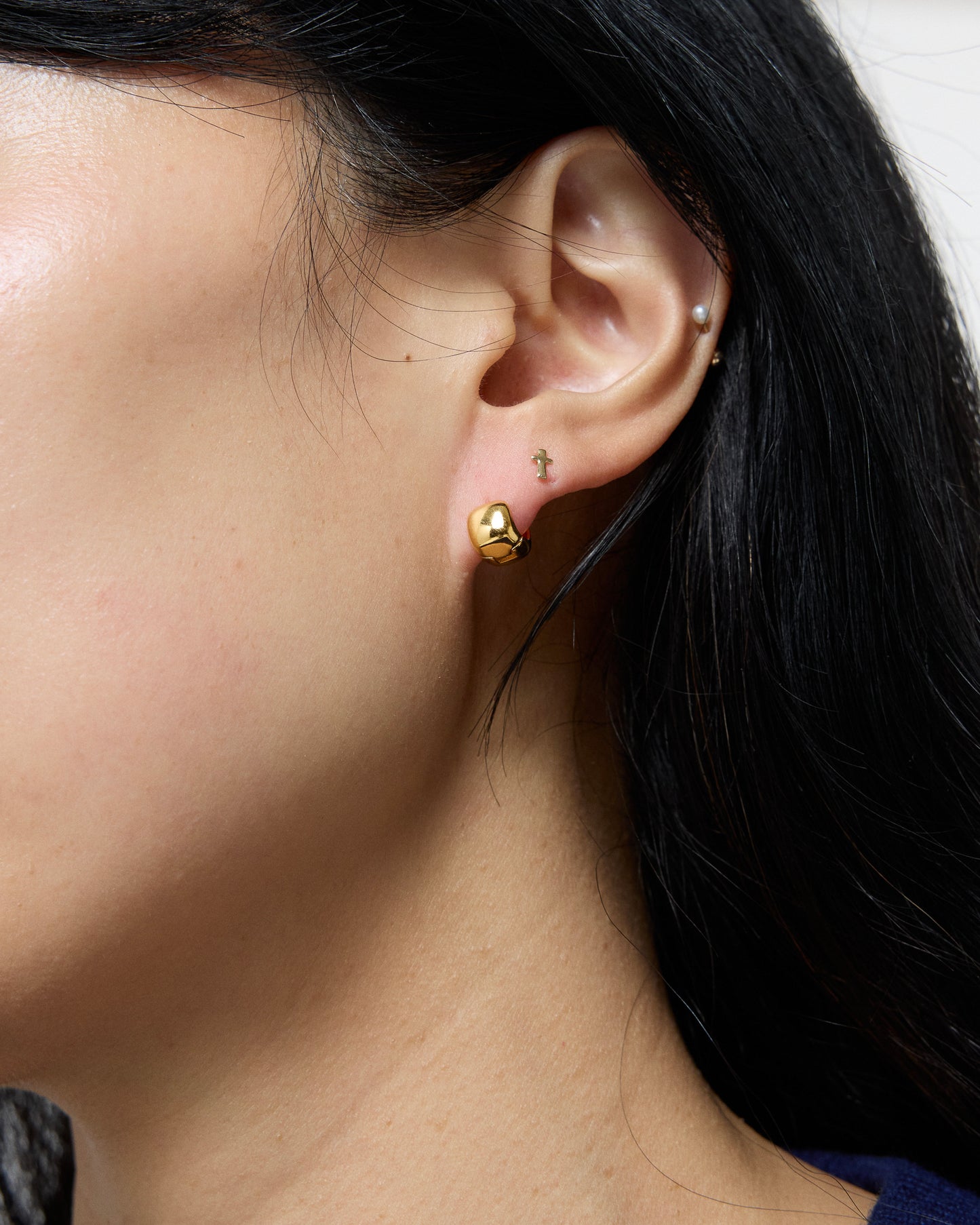 Close-up of a person wearing a gold earring