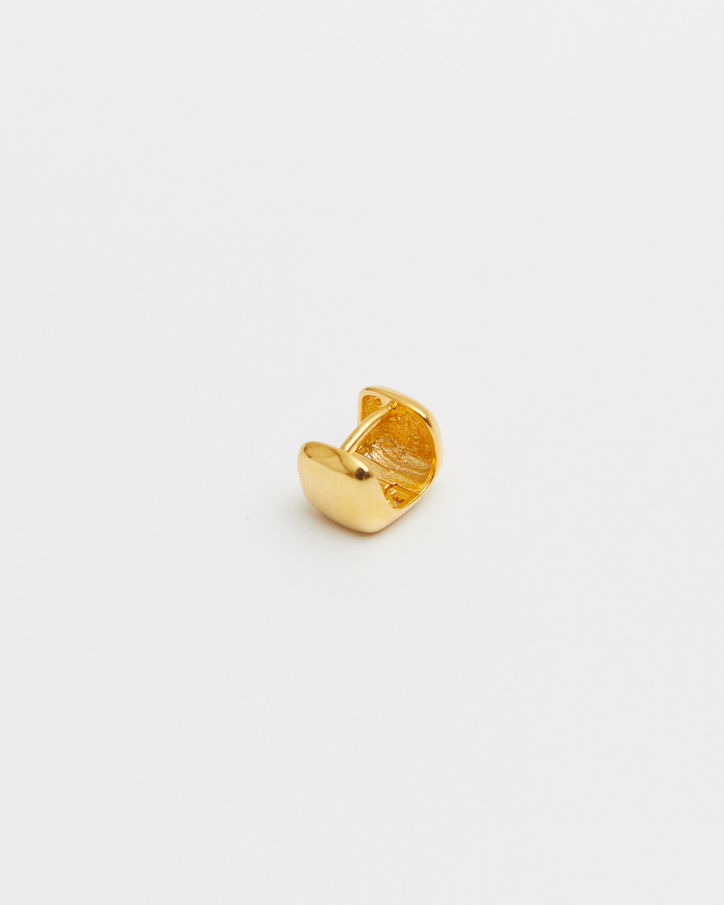 close-up of gold square stud earring held in hand, rounded cube design, glossy finish minimal jewelry