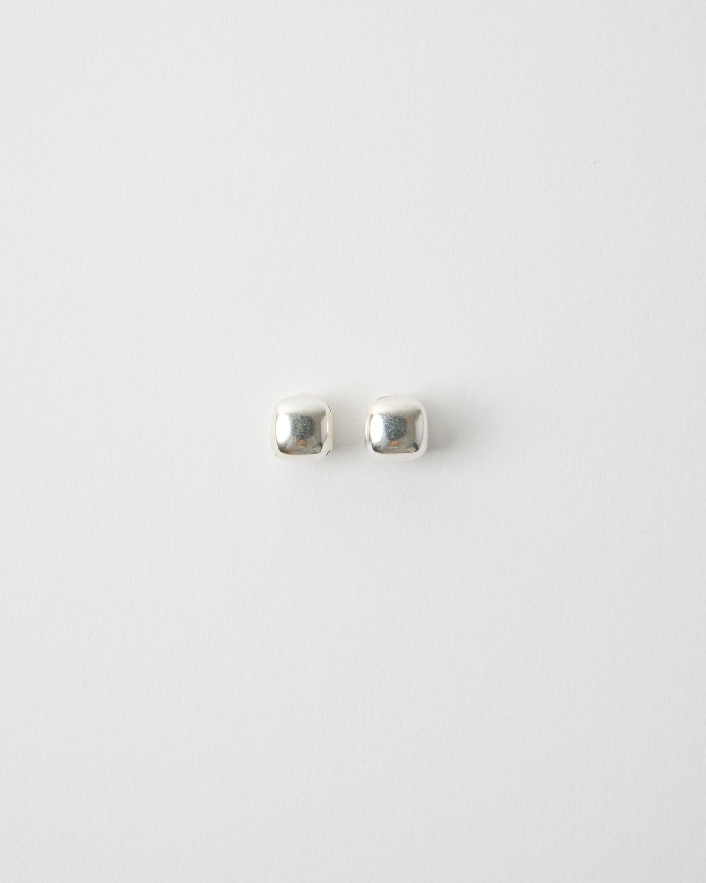 pair of sterling silver square stud earrings on white background, polished cube shape minimal jewelry, clean modern product shot