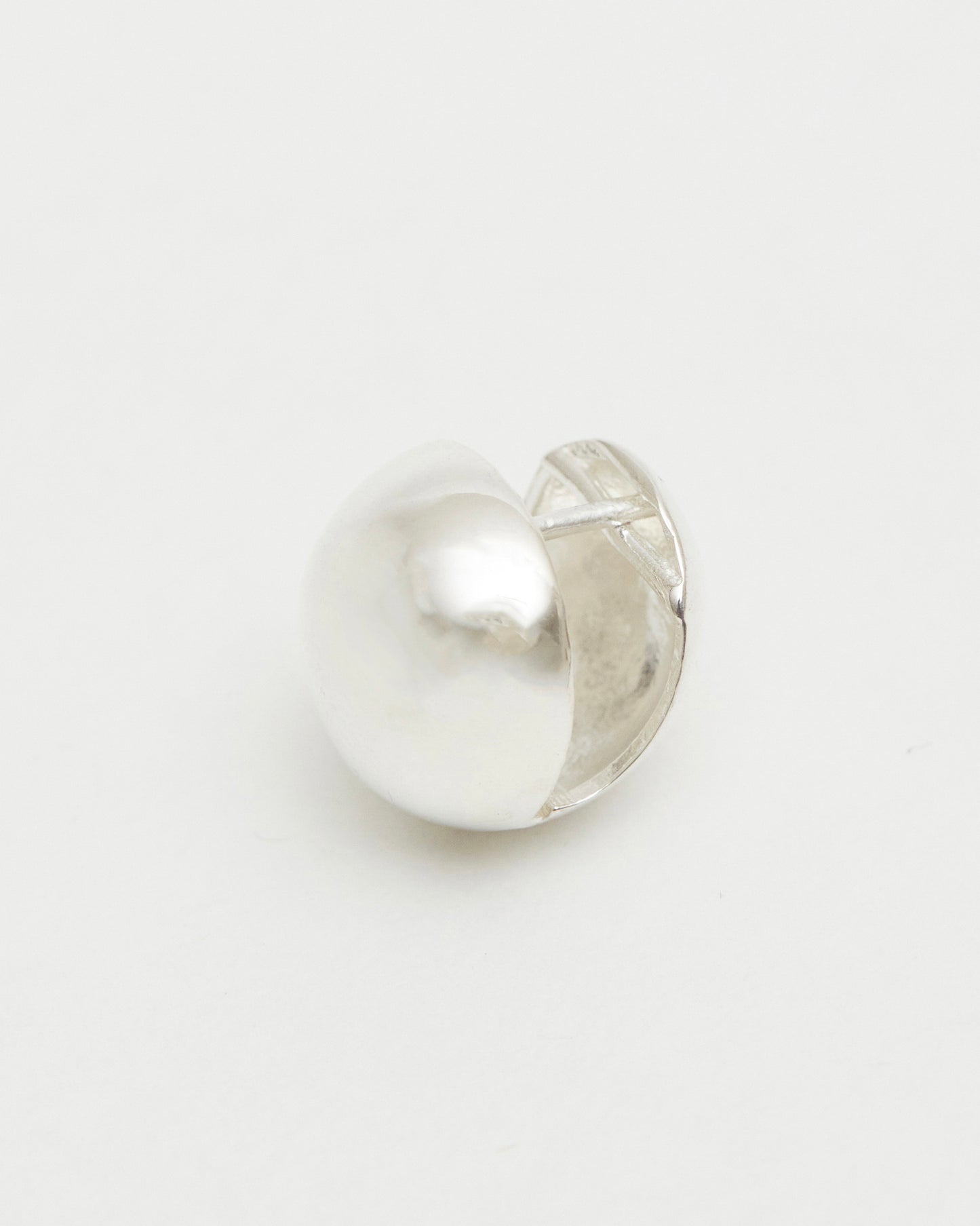 silver earring with a half-circle design on a light gray background