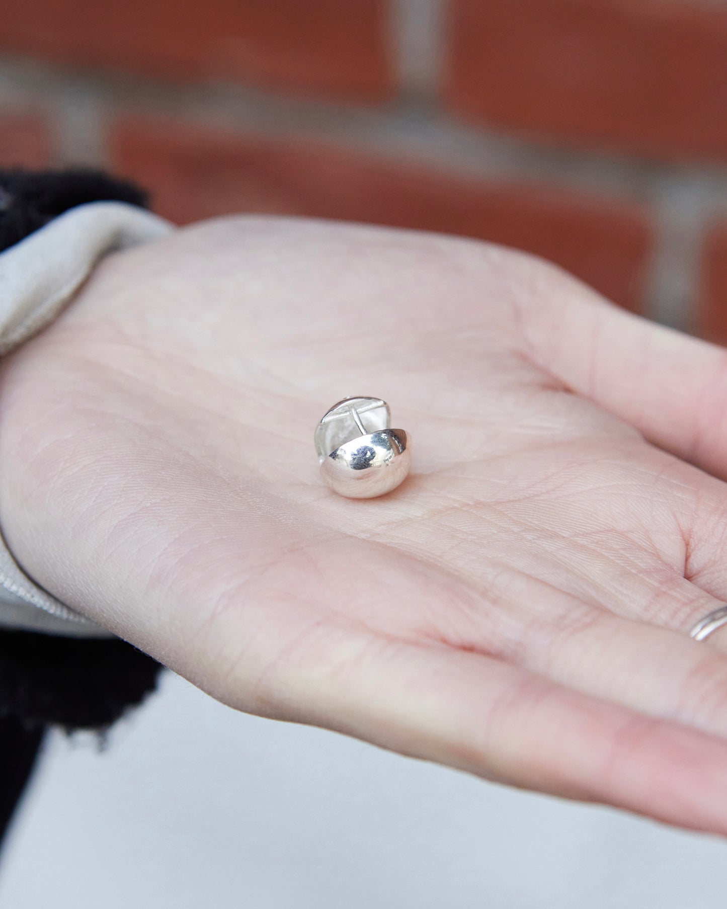 silver dome stud earrings on hand showing size scale minimal everyday jewelry