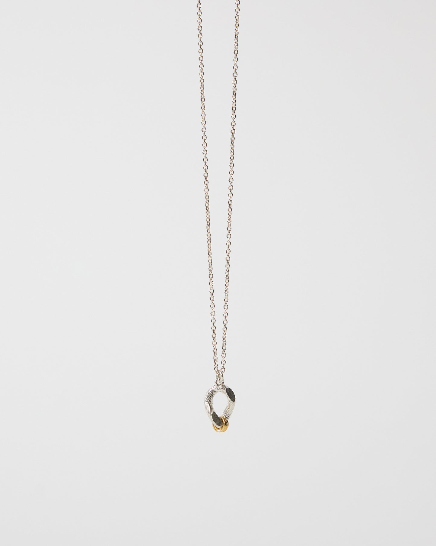 Detailed angled view of an organic mixed metal pendant necklace on chain