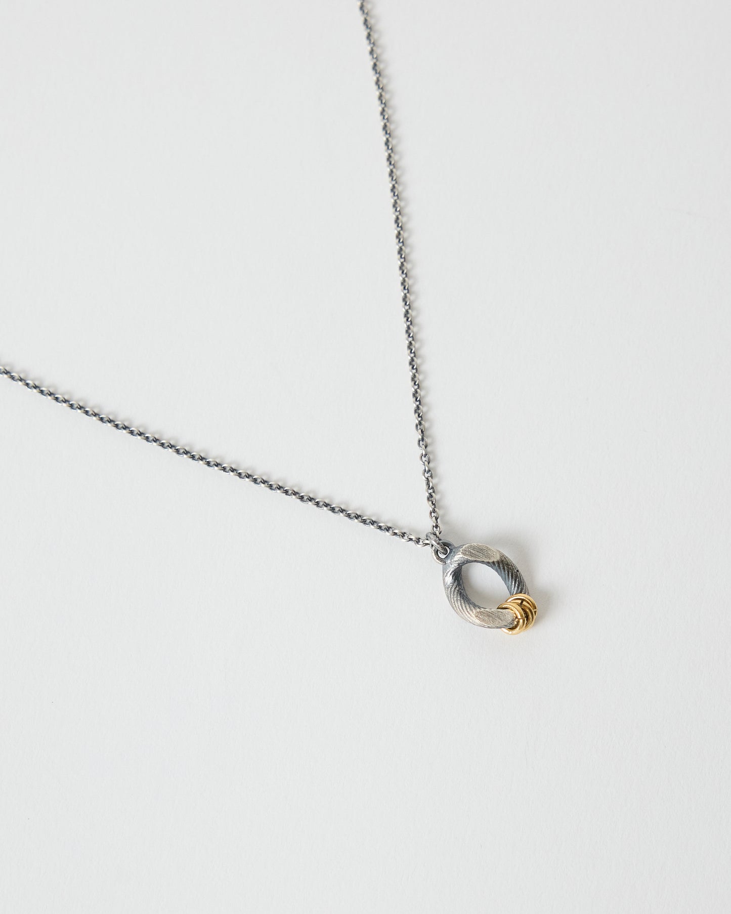 Detailed angled view of an organic mixed metal pendant necklace on chain