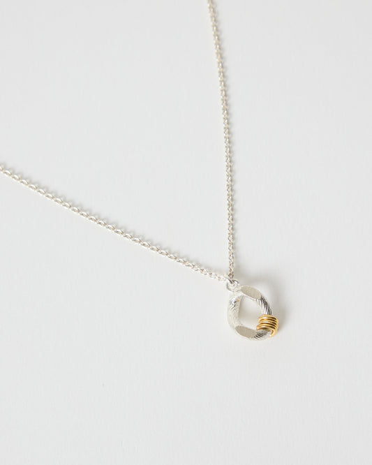 Close-up detail of textured sterling silver pendant with gold accent rings