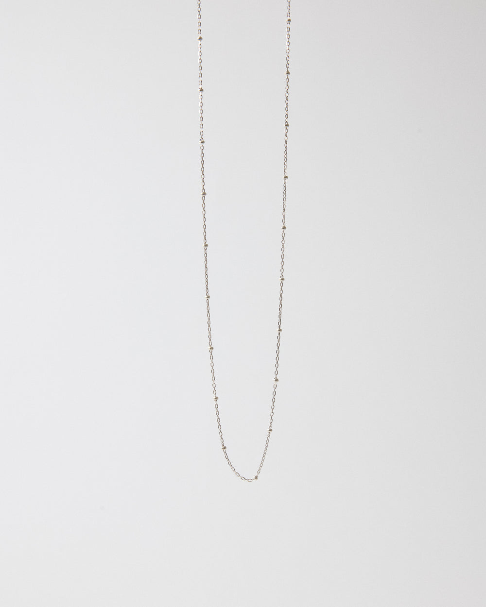 Sterling silver ball station chain necklace hanging on a light gray background – HANNA543 N1057 starlit dot chain