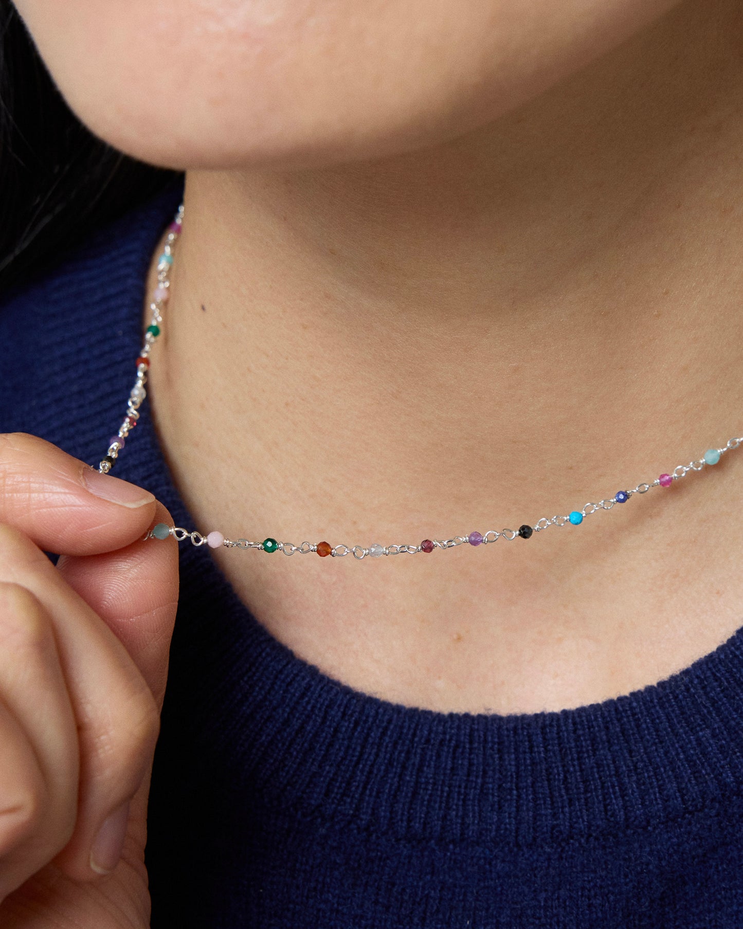 Close-up of colorful gemstone necklace layered around the neckline