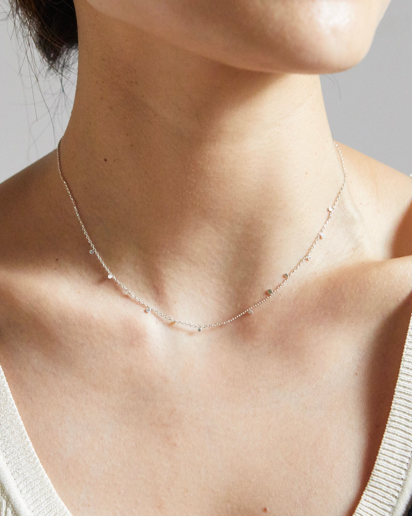 Close-up of silver necklace with tiny disc details on collarbone