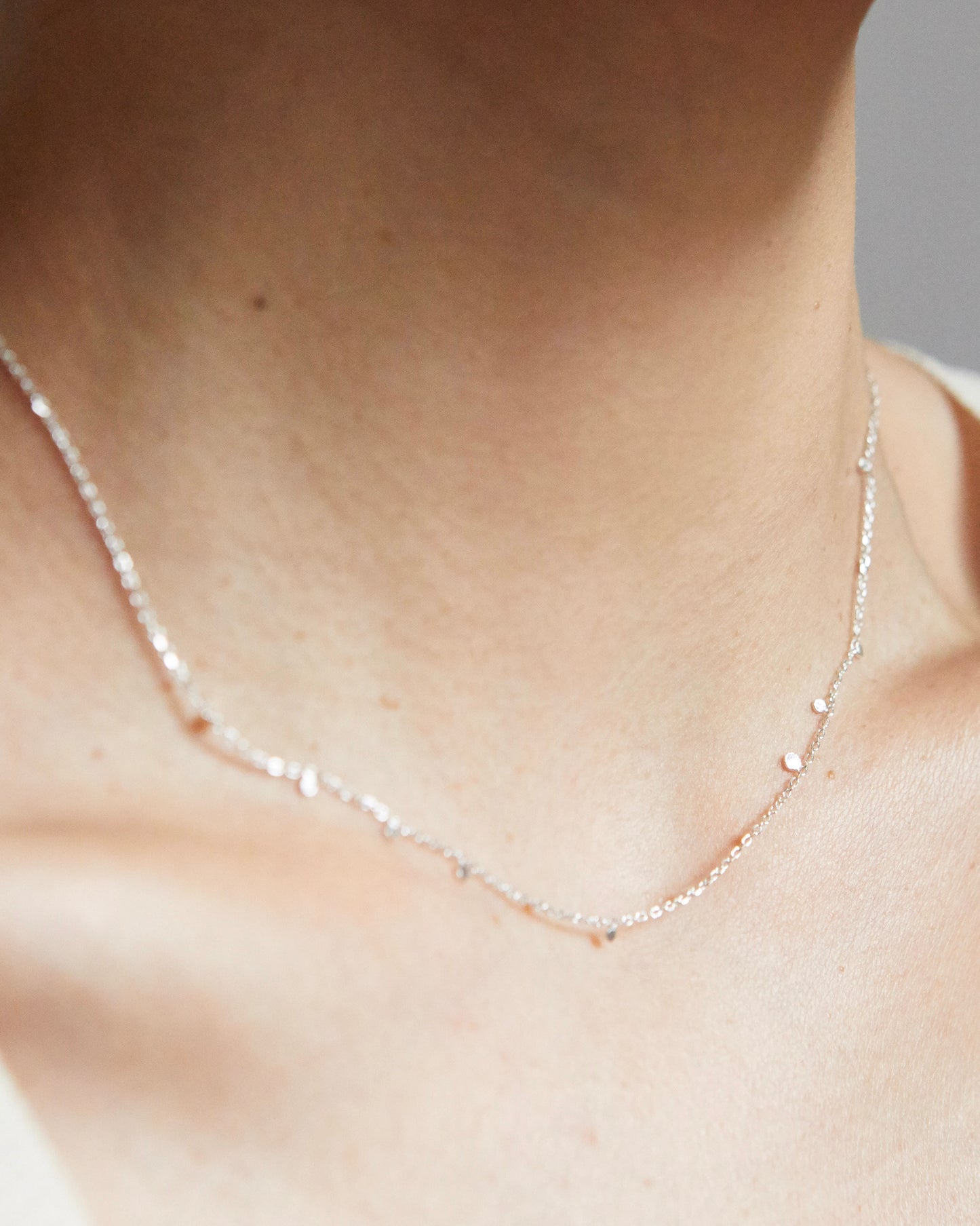 Close-up of silver necklace with tiny disc details on collarbone