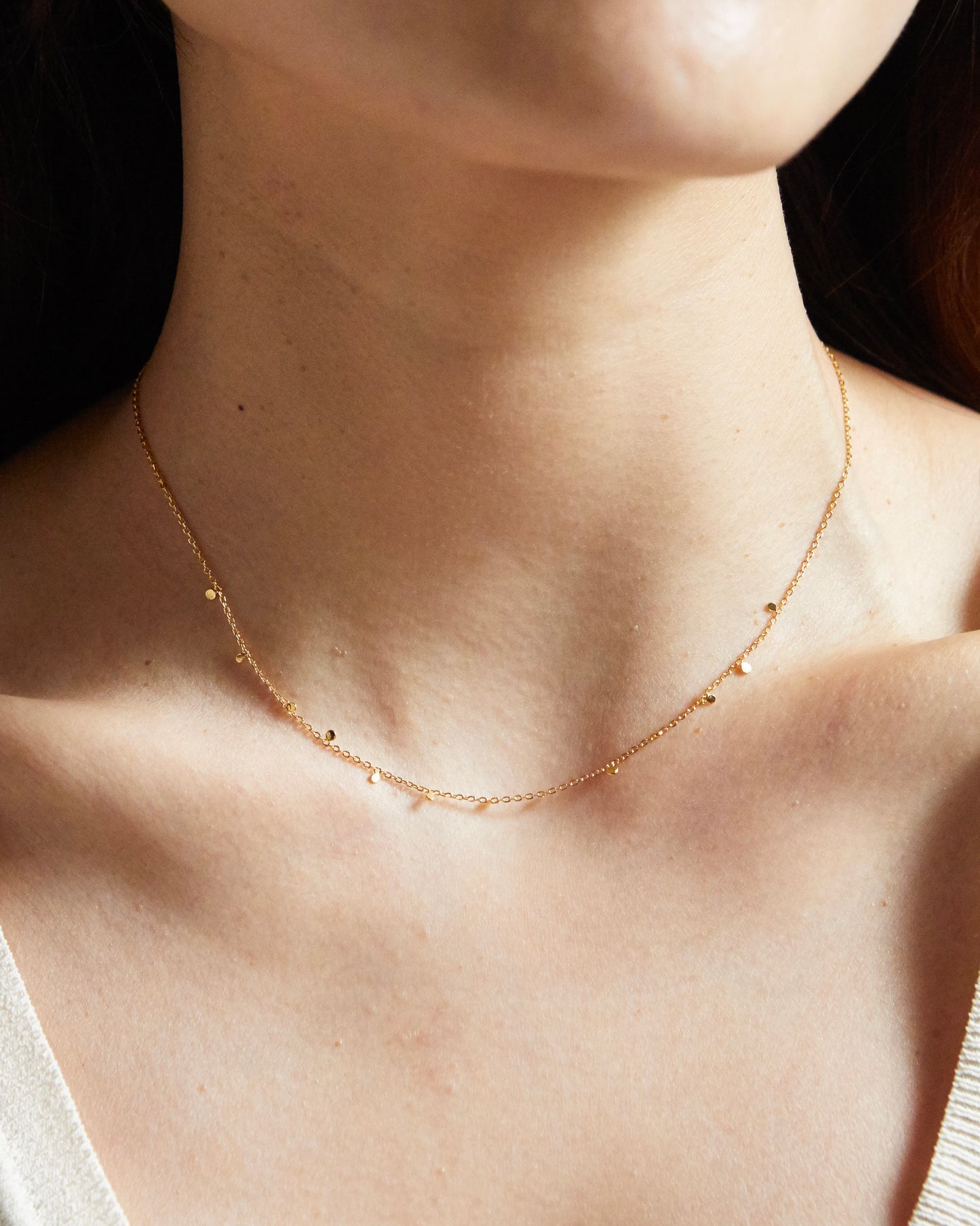 Close-up detail of silver necklace with small disc charms on chain