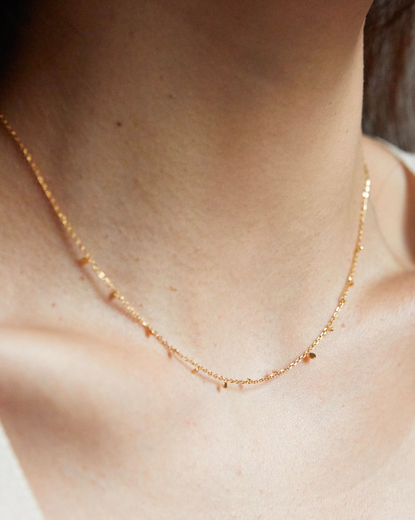 Gold necklace close-up showing small dangling discs along chain