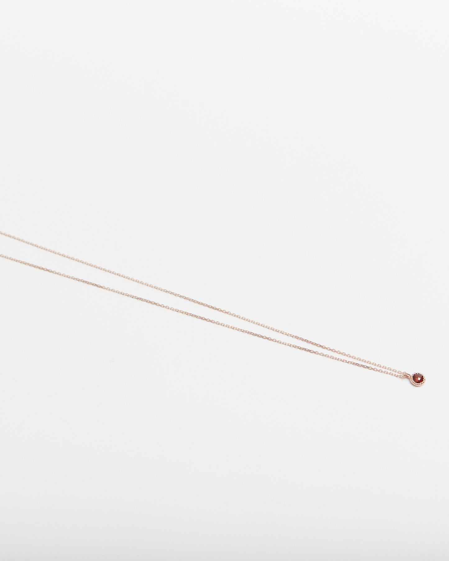 Thin gold chain necklace on a light gray background