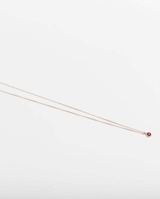 Thin gold chain necklace on a light gray background